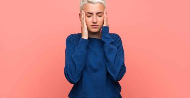 Teenager girl with white short hair over pink wall with headache