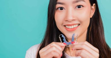 Teeth retaining tools after removable braces, Portrait young Asian beautiful woman smiling holding silicone orthodontic retainers for teeth, Orthodontics dental healthy care concept